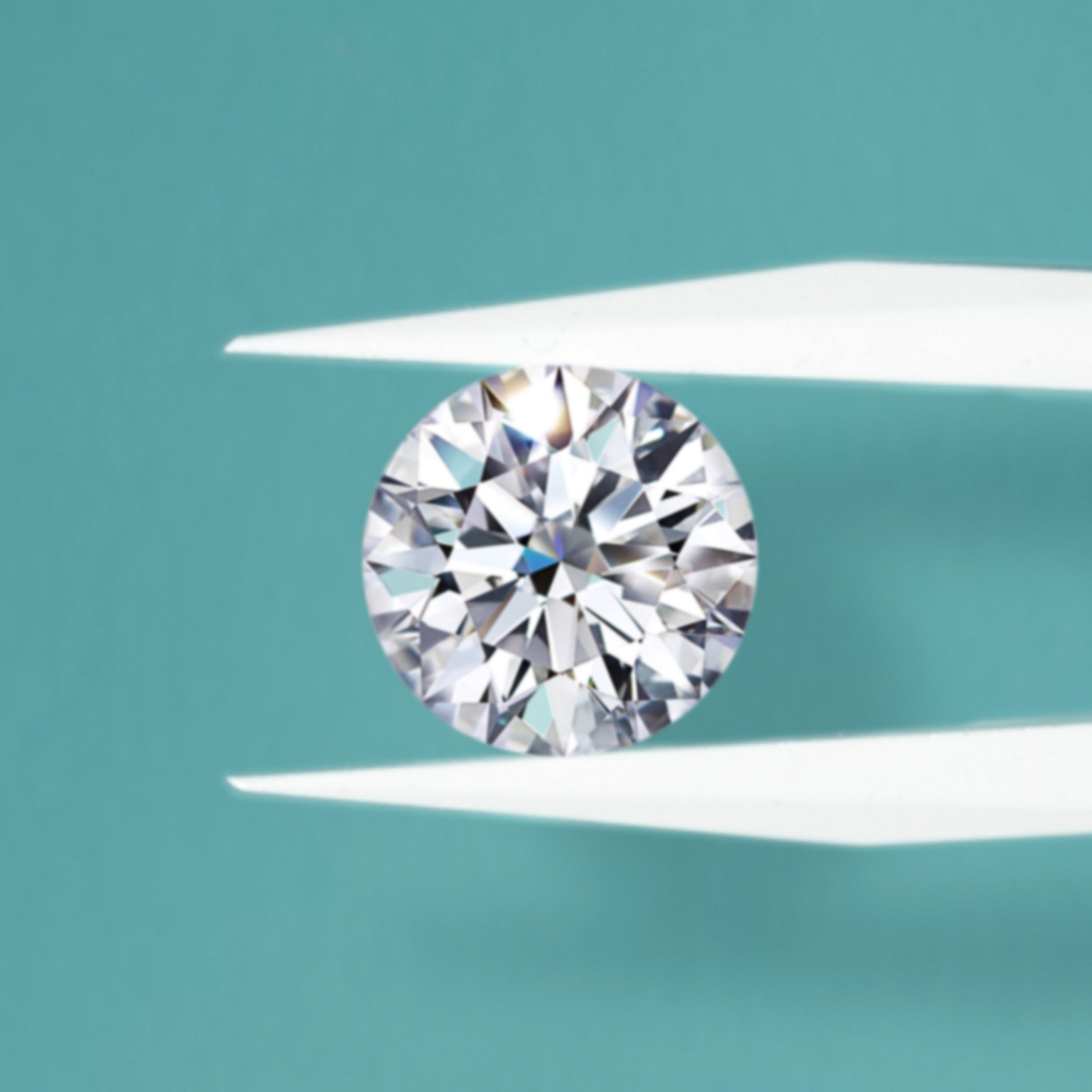 Løs diamant holdt i pinsett, fotografert mot ensfarget bakgrunn